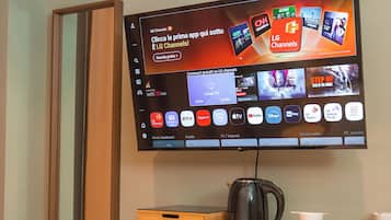 A flat-screen TV mounted on a wall displaying various streaming services and channels.