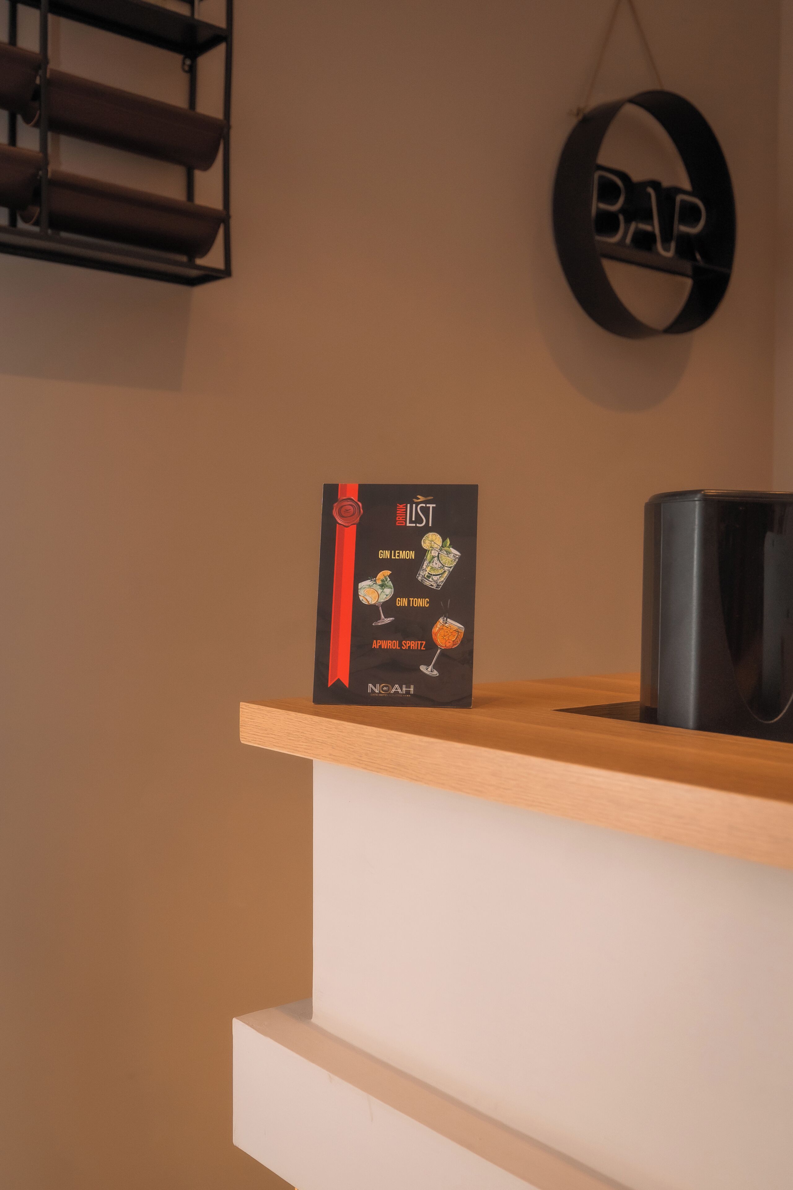 A bar area with a sign listing drinks and a black trash bin.