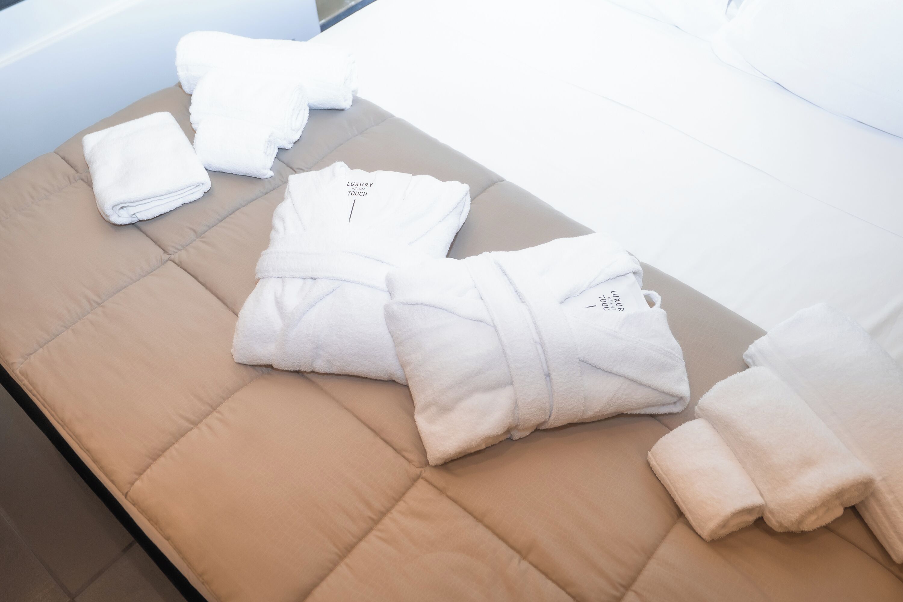 A neatly arranged set of towels on a cushioned bench in a hotel room.