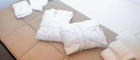A neatly arranged set of towels on a cushioned bench in a hotel room.