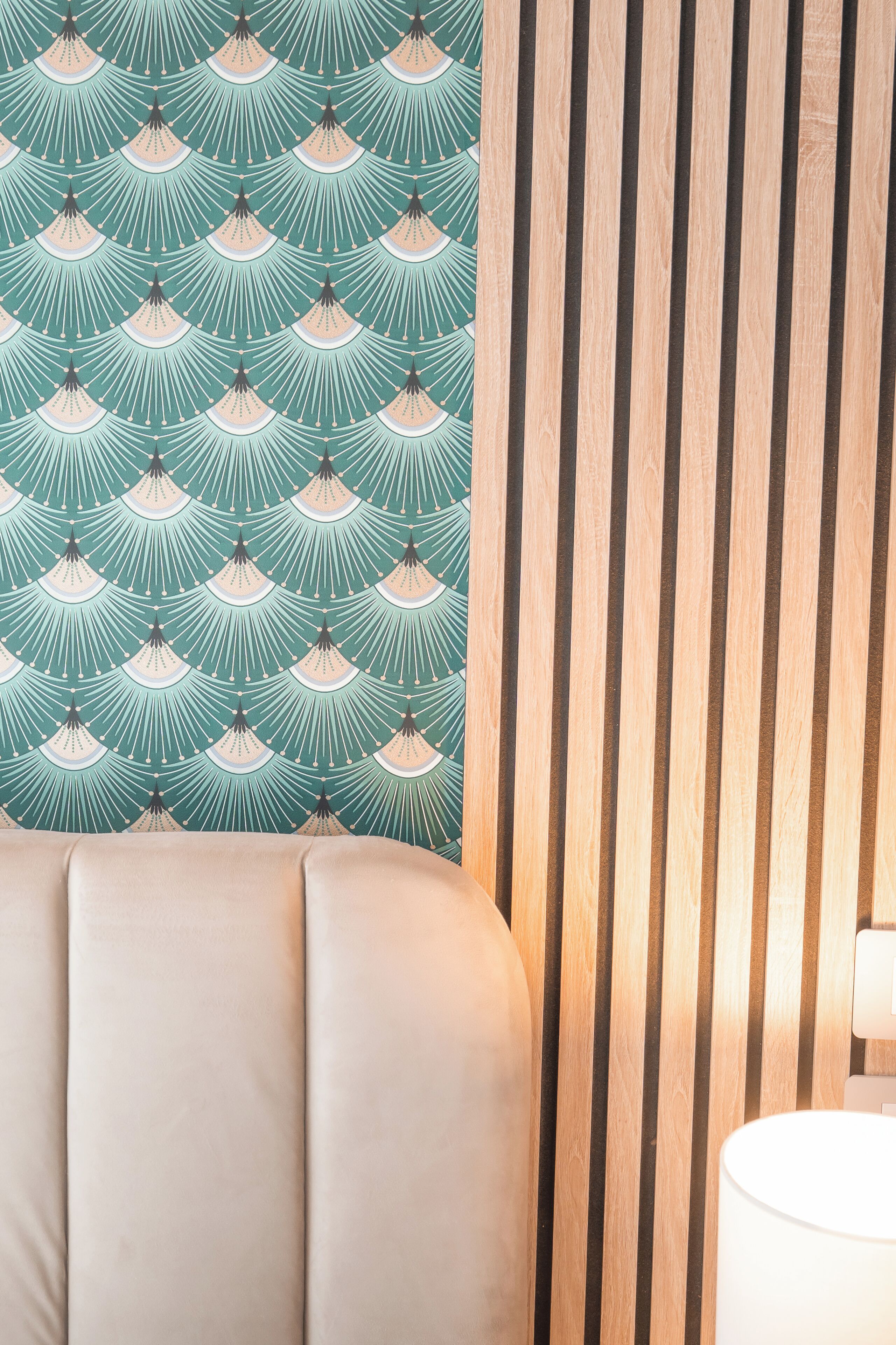 A room with a patterned wallpaper, a wooden slat wall, and a cushioned seating area.
