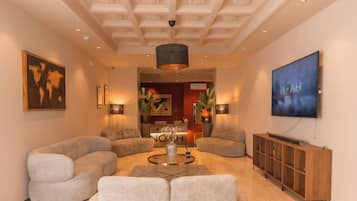A modern living room with a large sofa, a coffee table, and a television on the wall.