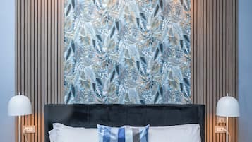 A hotel room with a large bed, two bedside lamps, a black headboard, and a patterned wall.