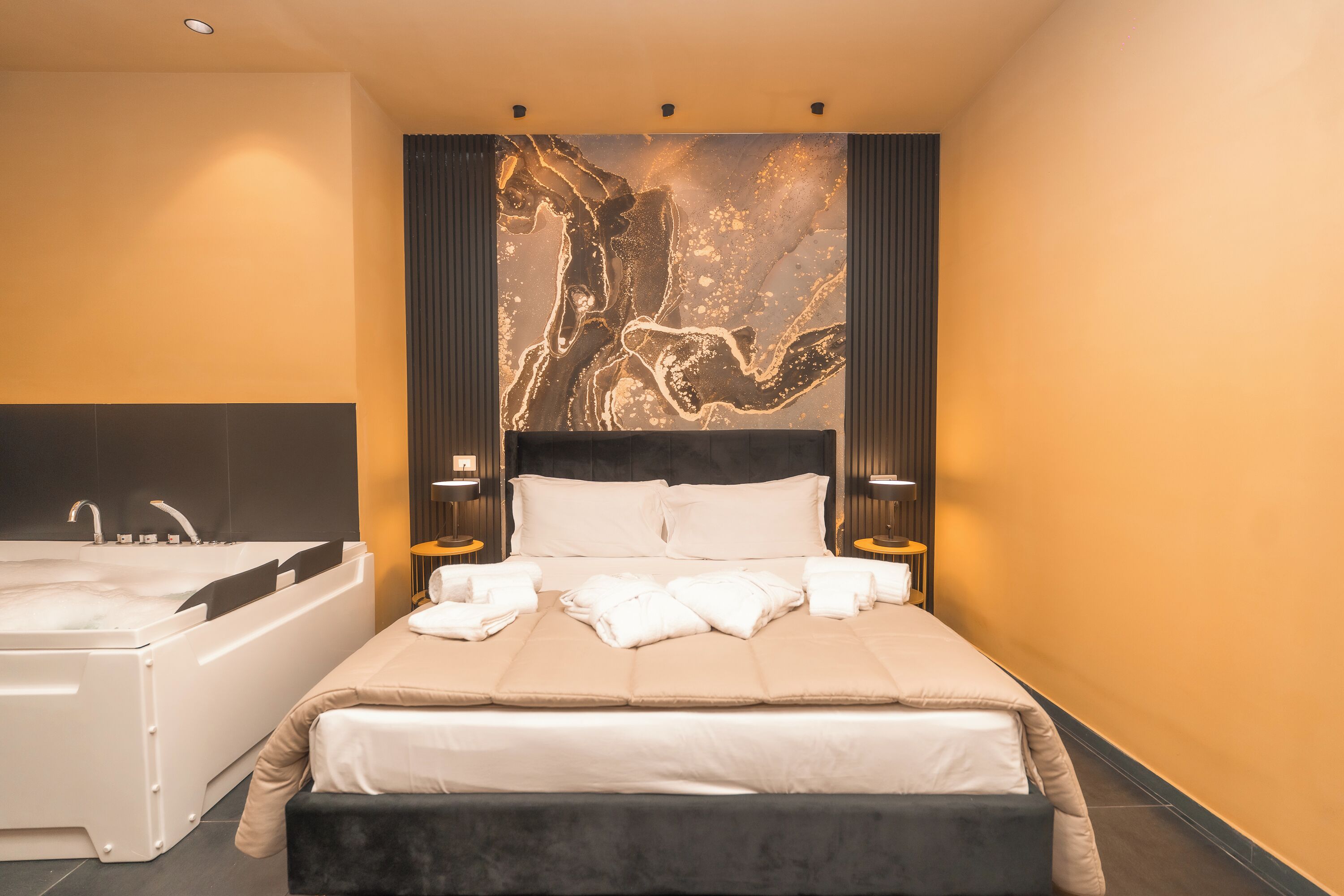 A hotel room with a large bed, a bathtub, and a wall-mounted artwork.