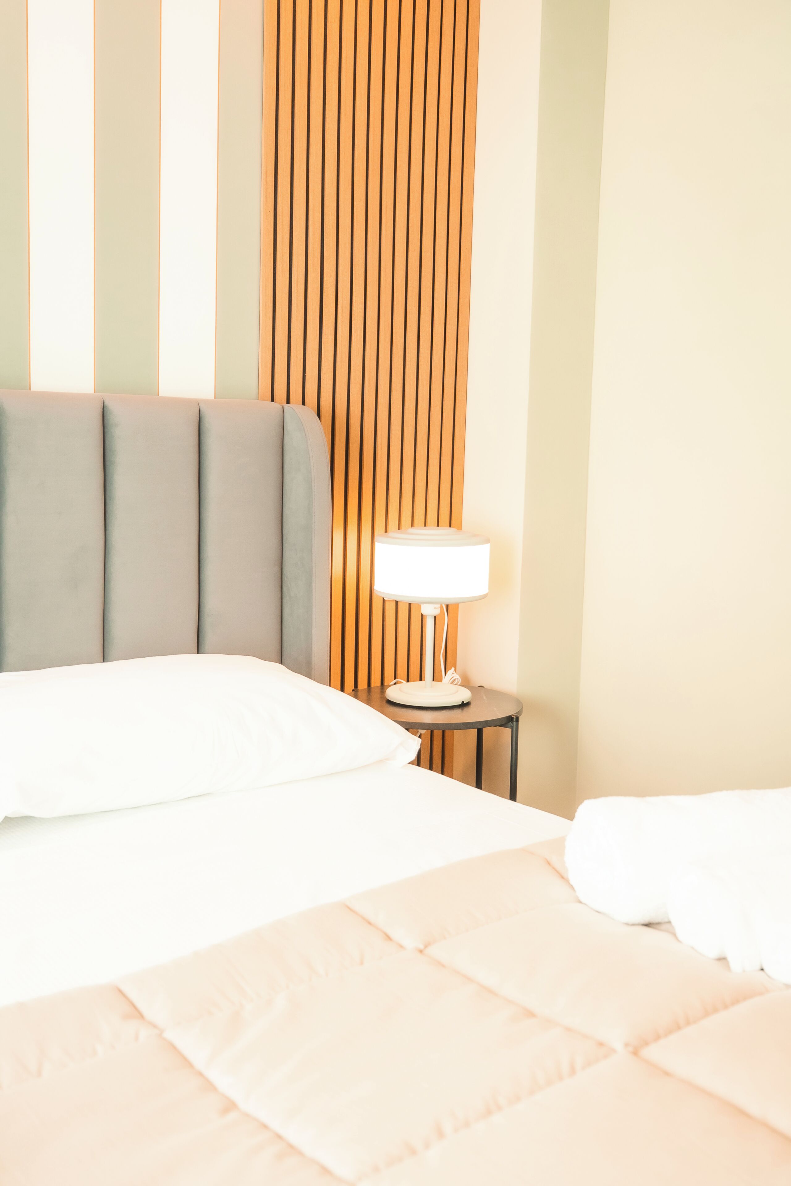 A hotel room with a bed, a nightstand, and a lamp.