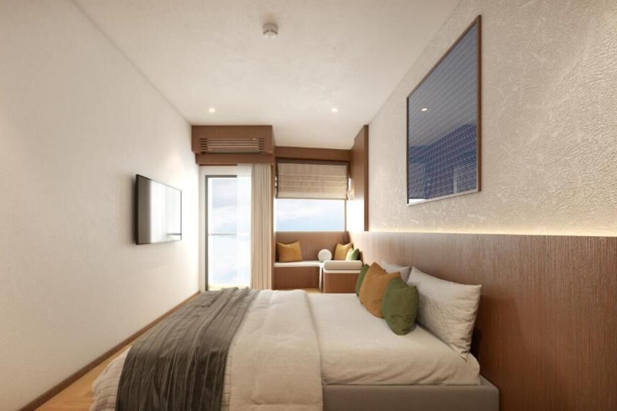 A modern hotel room with a large bed, a television, and a window with a view.