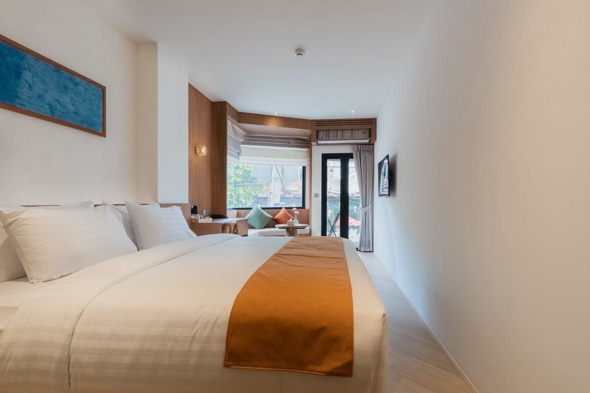 A hotel room with a large bed, a desk, and a view of the outdoors.