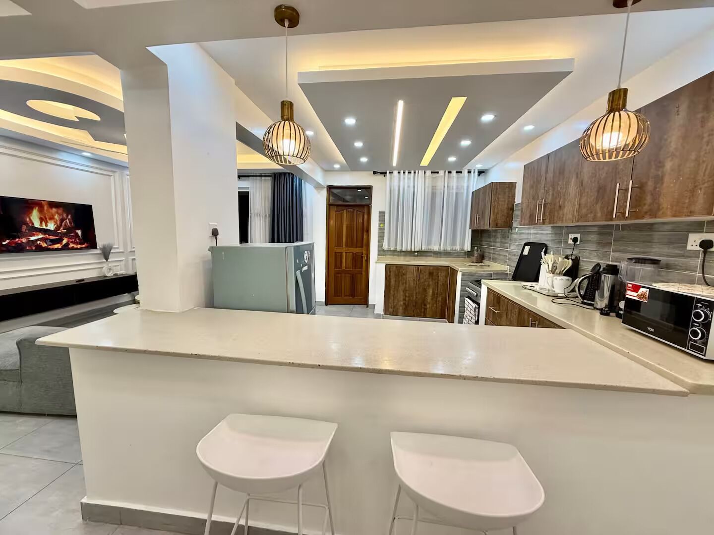Cozinha moderna com ilha central, banquetas e iluminação pendente.