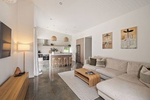 A modern living room with a sofa, coffee table, and a kitchen in the background.