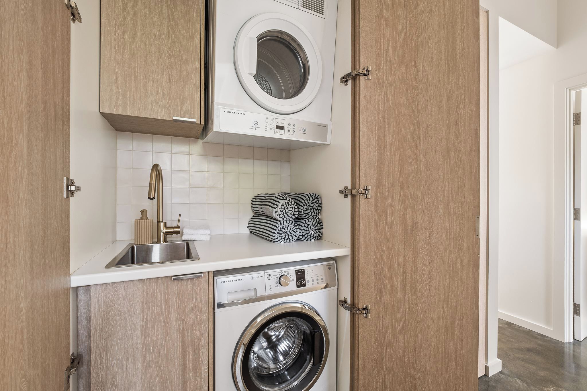 Un espace buanderie compact comprenant un lave-linge, un sèche-linge et un évier.