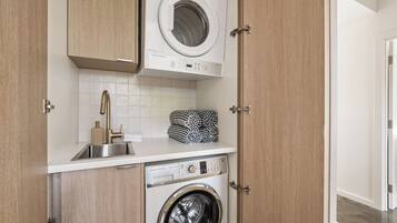 Un espace buanderie compact comprenant un lave-linge, un sèche-linge et un évier.