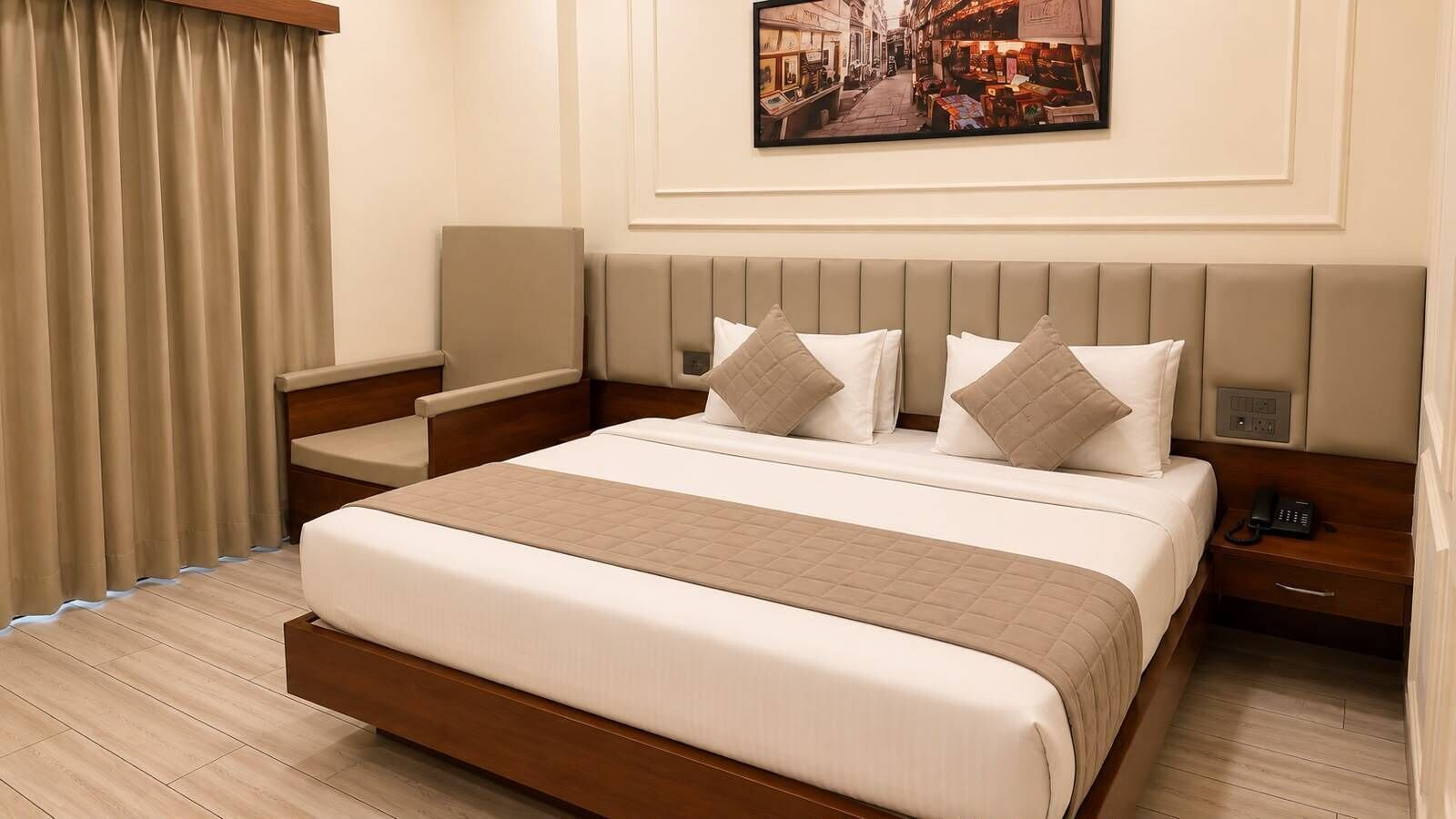 A hotel room with a large bed, bedside tables, a nightstand, a telephone, and a painting on the wall.