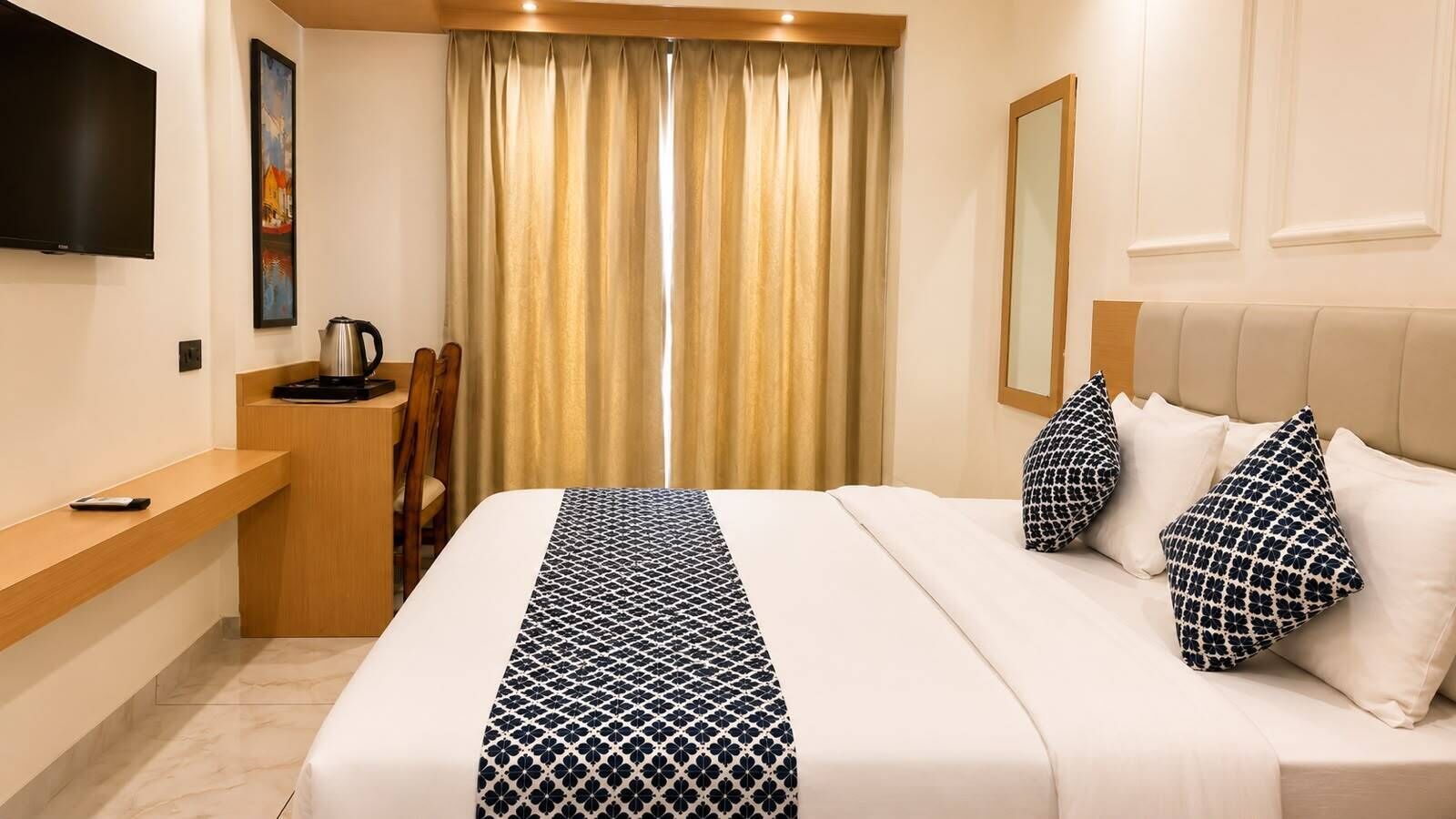 Ein Hotelzimmer mit Bett, Schreibtisch, Fernseher, einem Fenster mit Vorhängen und einem Spiegel.