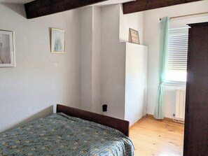A bedroom with a bed, a radiator, and a window with curtains.