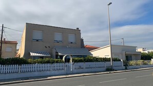 A building with a flat roof, a white picket fence, and a street in front.