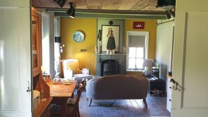 A cozy room with a fireplace, a dining table, and a comfortable sofa. - Charming holiday cottage with a private garden. (Irnsum)