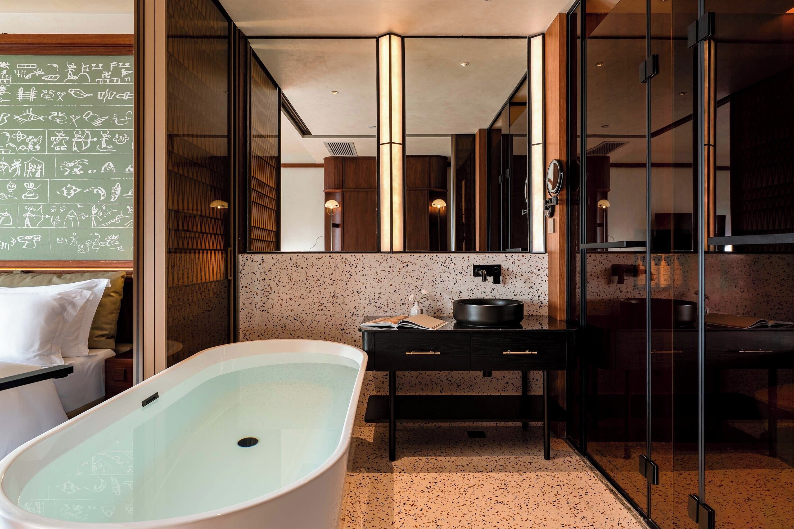 A modern bathroom with a freestanding bathtub, a dark vanity, and a large mirror.