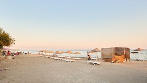 Una platja amb gandules, ombrel·les i una petita cabana.