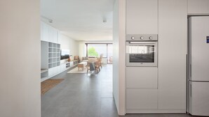 Eine moderne Küche mit weißen Schränken, einem Backofen und einem Kühlschrank.