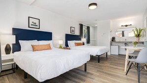 Et hotelværelse med to senge, et lille tekøkken og et spiseområde.