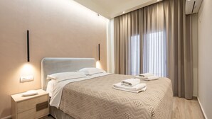 Een moderne hotelkamer met een opgemaakt bed, een nachtkastje met een lamp, en een groot raam met gordijnen.