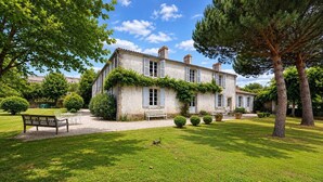 A stone building with a garden, a bench, and a tree.