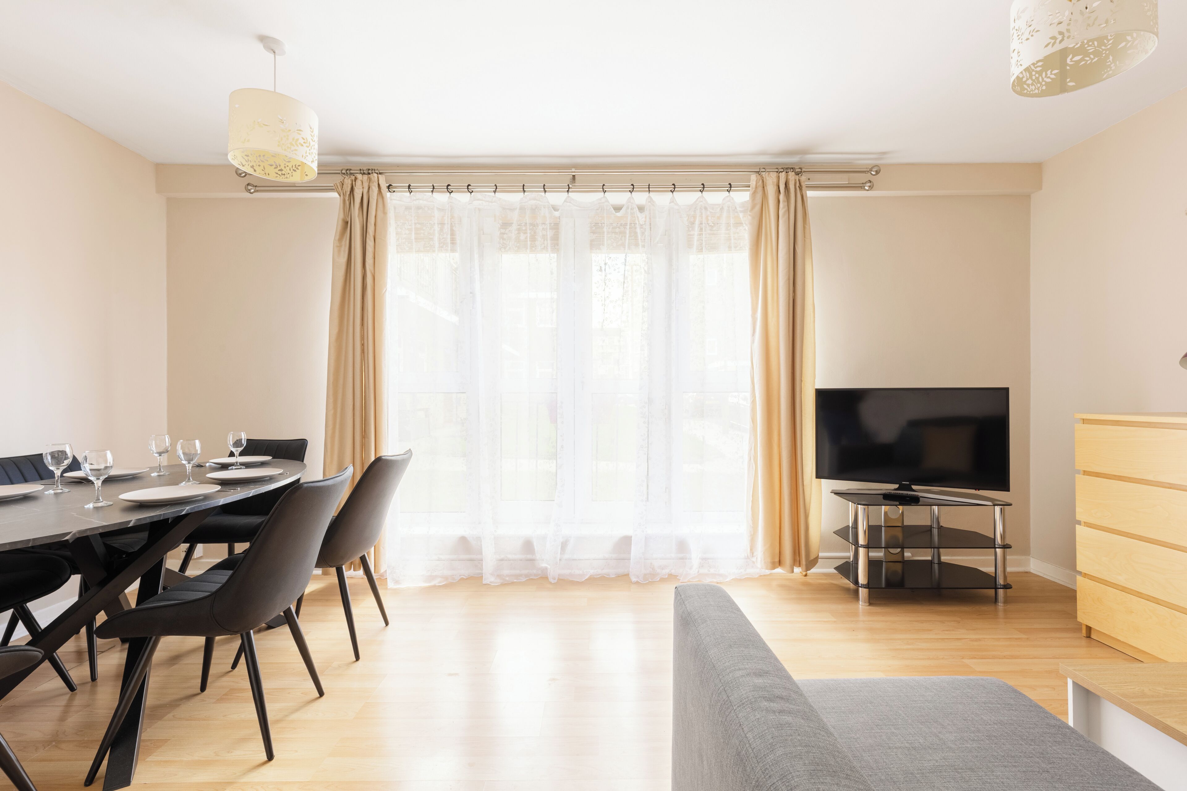 A modern living room with a dining area, a flat-screen TV, and a sofa.