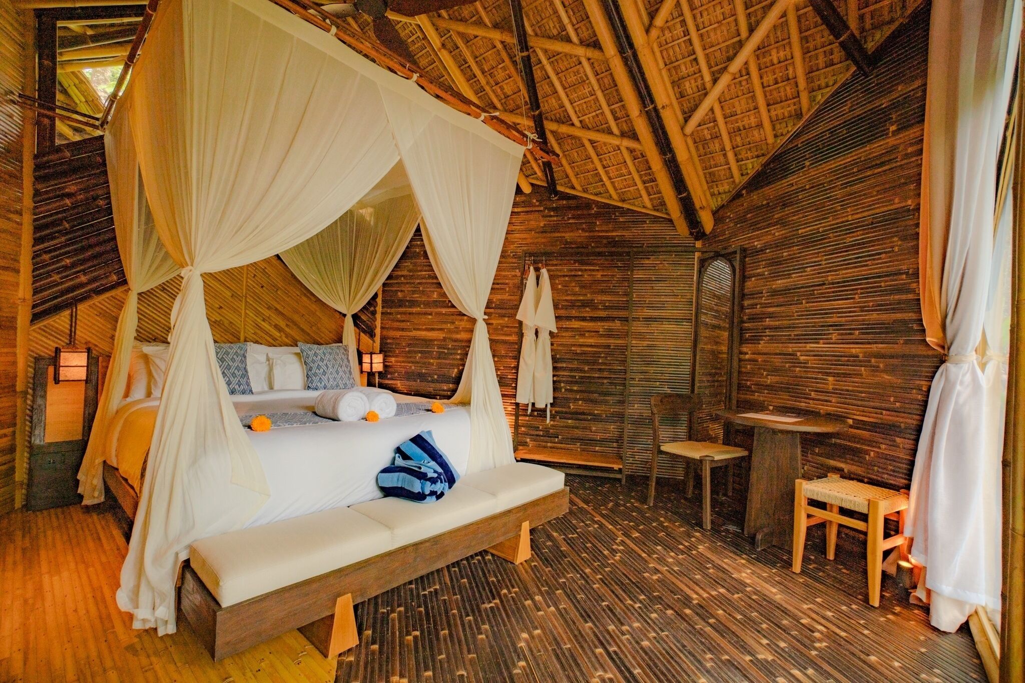 Ein Zimmer mit einem Bett, das unter einem Baldachin steht, einem kleinen Tisch und einer Bank.