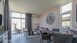 Moderni olohuone, jossa on ruokailutila, suuret ikkunat ja näkymä ulos.