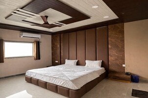 Un dormitorio moderno con una cama grande, cabecera integrada y ventilador de techo.