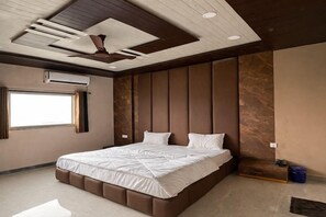 Un dormitorio moderno con una cama grande, cabecera integrada y ventilador de techo.