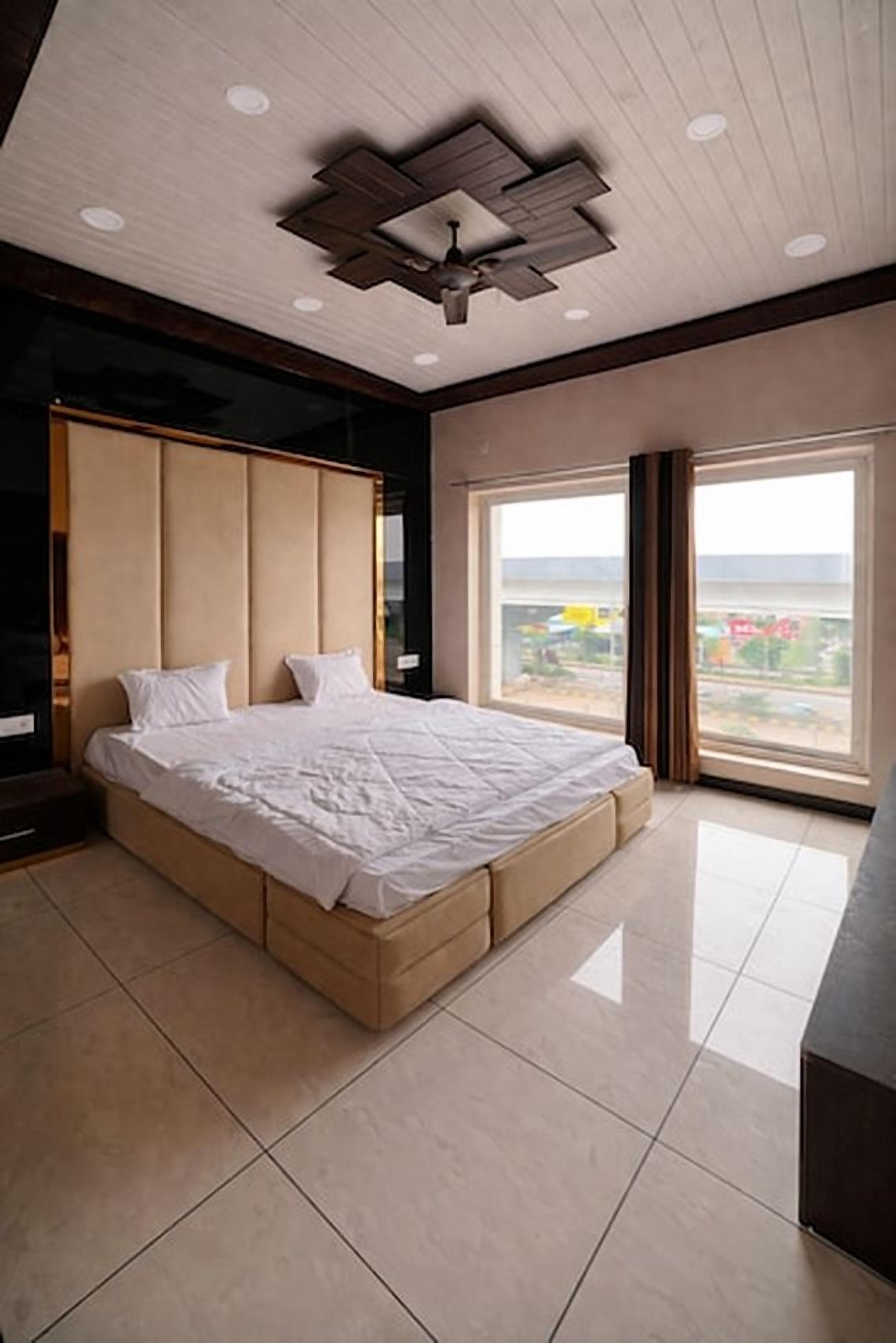 A modern bedroom with a large bed, a ceiling fan, and a view of the city through the window.