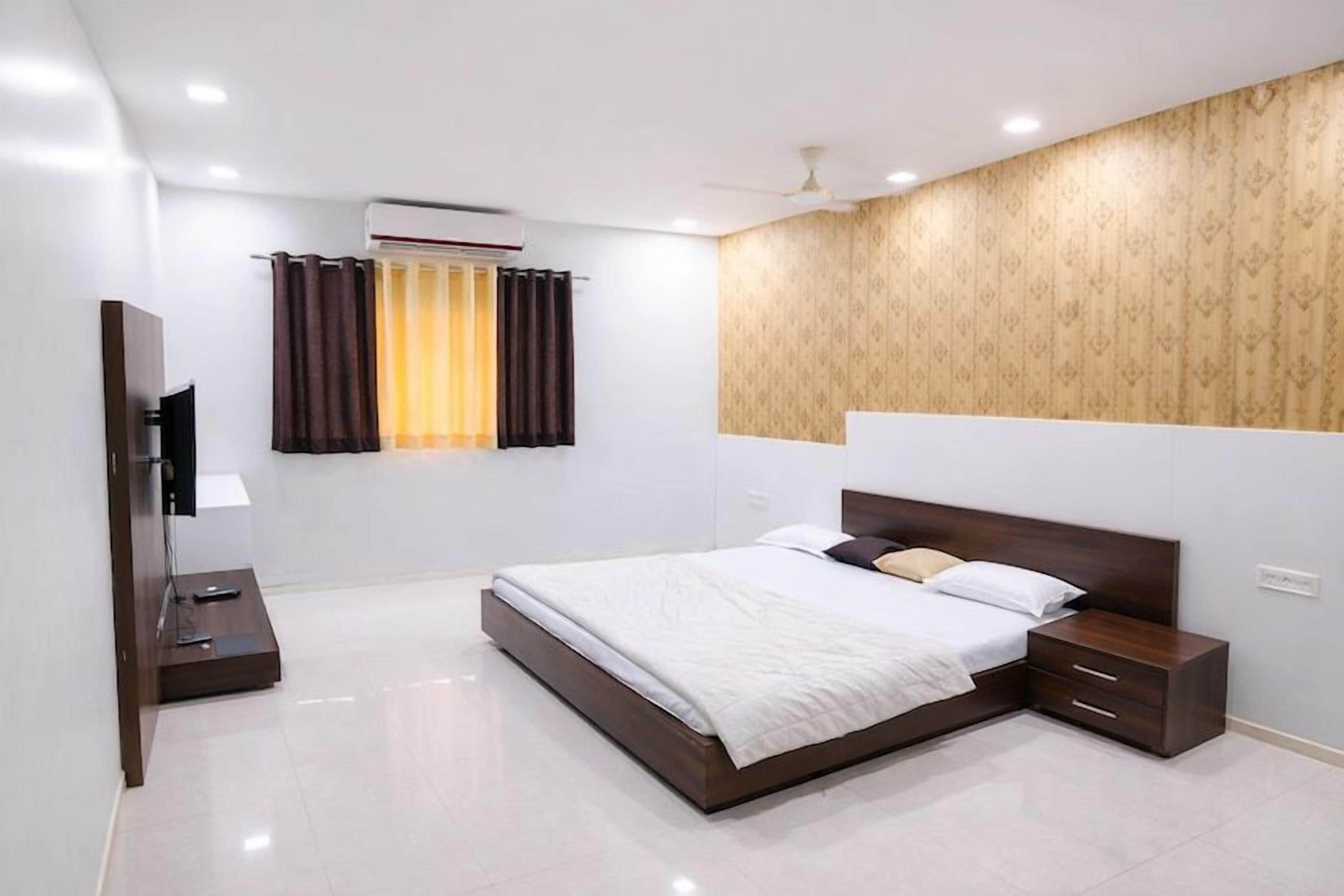 A modern hotel room with a large bed, bedside tables, a flat-screen TV, and a window with curtains.