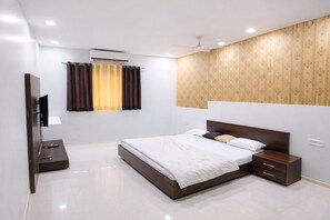 A modern hotel room with a large bed, bedside tables, a flat-screen TV, and a window with curtains. - The Golden Wings Hotel  (Dewas)