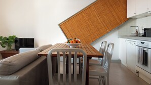 A modern kitchen with white cabinets, a built-in oven, and a dining area with a wooden table and metal chairs.
