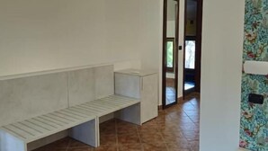 A room with a bench, a small table, and a door leading to another area. - B&B Cascina del Gelso (Santena)