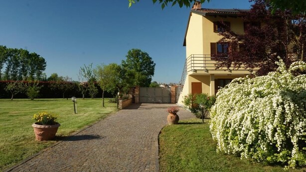 A two-story house with a paved driveway leading to a gated entrance. - B&B Cascina del Gelso (Santena)