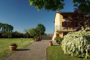 Una casa de dos pisos con un camino pavimentado que conduce a una entrada con portón.