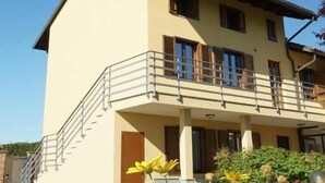 A two-story building with a balcony and a flower garden in front. - B&B Cascina del Gelso (Santena)