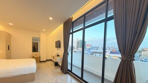 A modern hotel room with a large window, a bed, a vanity with a mirror, and a flat-screen TV. - The Sky Plus (Sihanoukville)