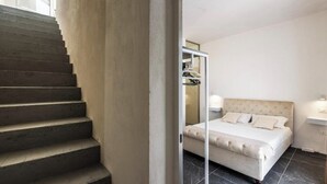 Ein Schlafzimmer mit einem Bett, einem Nachttisch, einer Kommode und einer Treppe.
