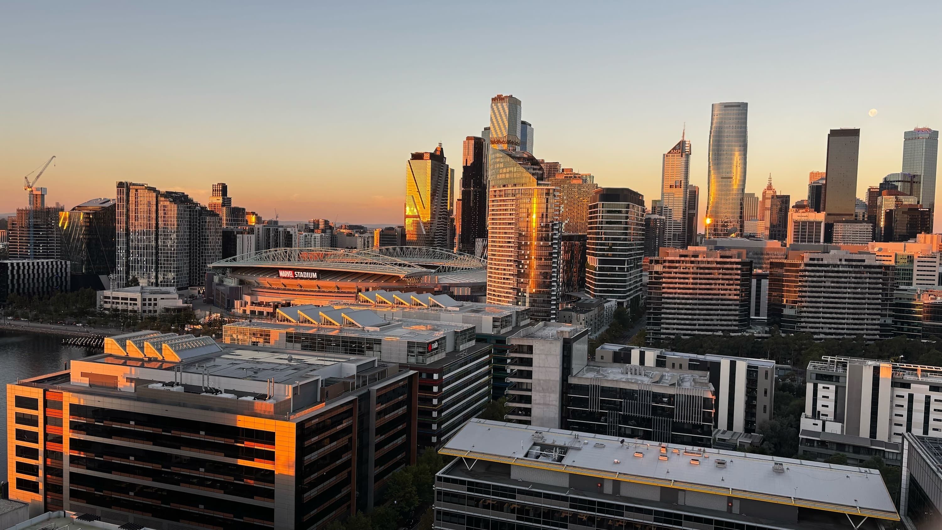 A cityscape with modern high-rise buildings, a stadium, and a parking structure.