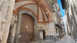 Eine enge Kopfsteinpflasterstraße mit einem großen, gewölbten Durchgang zu einem Gebäude mit einer Holztür und einem kleinen Fenster.