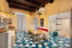 A kitchen with a wooden table, chairs, a hanging light fixture, and a tiled floor. - Annamaronna Home – Spacious Apartment with Balcony, Wi-Fi & AC in Naples Center (Napoli)