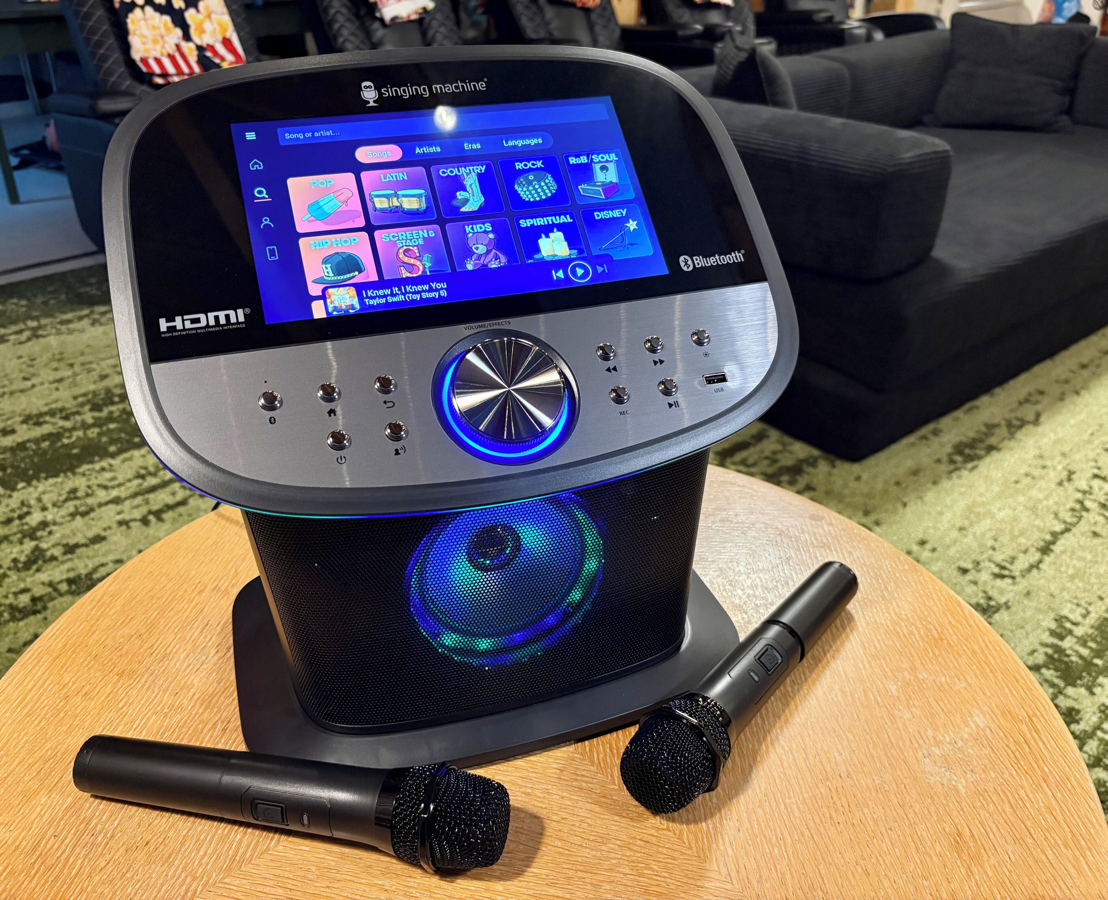 Kannettava äänilaite, jossa on näyttö, joka esittää kappaleluettelon, äänenvoimakkuuden säätönuppi ja USB-portti.