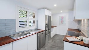 Une cuisine moderne avec des meubles blancs, des appareils en acier inoxydable et un plan de travail en bois.