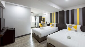 Quarto de hotel com duas camas, uma escrivaninha, uma cadeira e uma televisão.