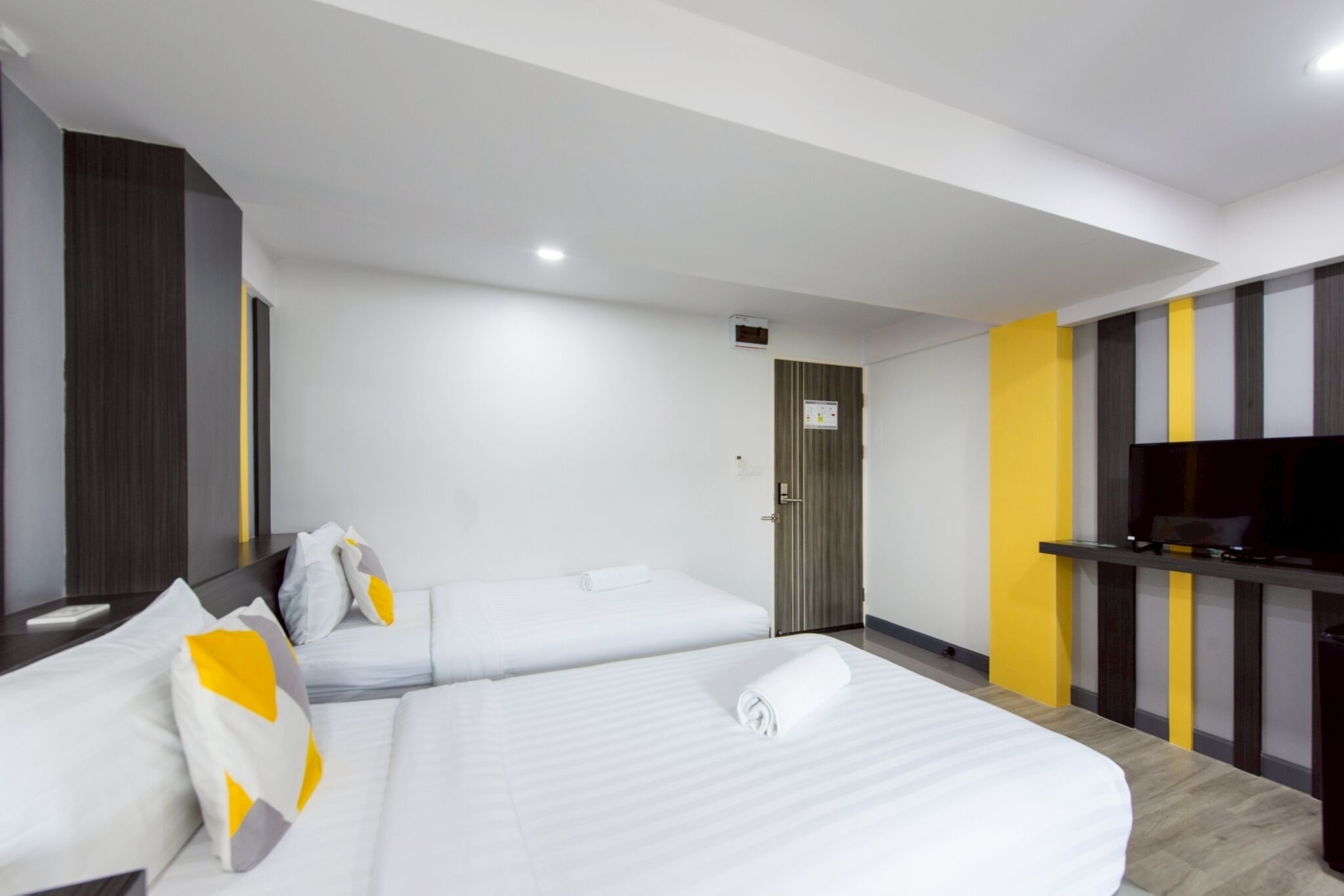 A hotel room with two beds, a flat-screen TV, and a wooden floor.