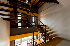 A multi-level wooden staircase with metal railings, connecting different floors of a building. - Riski Residence Bangbuathong (Bang Bua Thong)