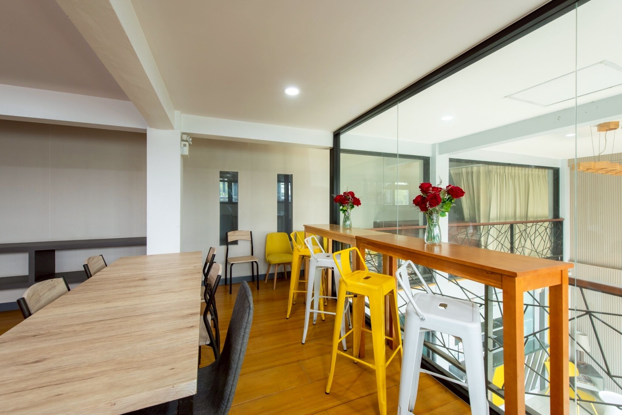 A modern meeting room with a wooden table, yellow and white chairs, and a glass partition.